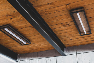 exhibition luminescent lamp on the wooden ceiling between the iron beams, in the design solution of...