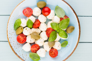 Delicious caprese salad with ripe cherry tomatoes and mini mozzarella cheese balls with fresh basil leaves.