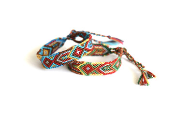 Tied DIY friendship bracelets with Indian colorful pattern handmade of thread on white background