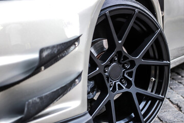 Close up of a wheel of a sports car. Black car rim with low profile rubber.