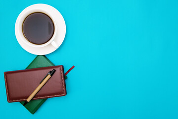 Notepad and pen on a blue background. Soft leather cover and paper pen.