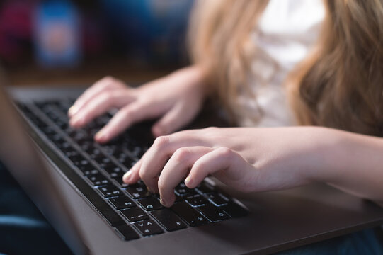 Childrens hands typing laptop keyboard in their room. Teaching children and adolescents to use computer technology