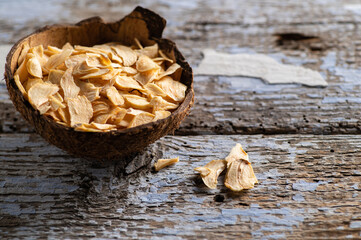 fragrant dry garlic in flakes in a coconut bowl on an old wooden background, top-side view, empty...