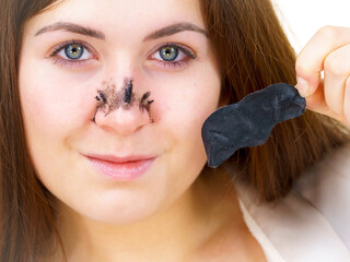 Woman removing pore strips mask from nose