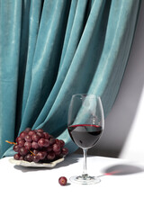 Wine glass and grapes on a concrete podium over a white background