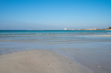 Sabbia bianca con mare trasparente e cielo azzurro.