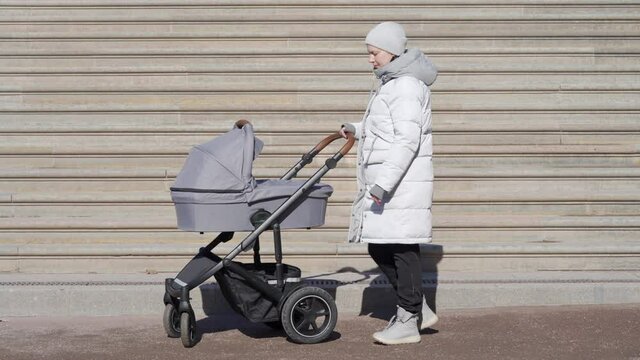 Mother with baby stroller on a walk against the steps of staircase in early spring, woman pushing baby pram on path in Catherine Park in the town of Tsarskoye Selo Pushkin. High quality 4k footage