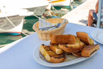 Grilled wheat bread with herbs on a white plate. Naoussa, Paros Island, Greece.