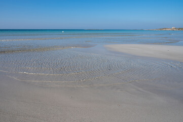 Sabbia bianca con mare trasparente e cielo azzurro.