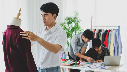 Asian dressmaker measuring apparel on dummy