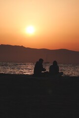 Young couple of lovers looking at the sea on sunset