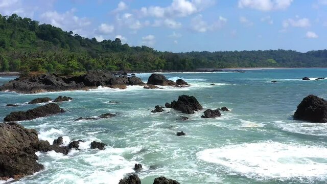 Drone flies over the stony coast with sea, waves and clouds in Corkovado National Park on Osa Peninsula, Costa Rica