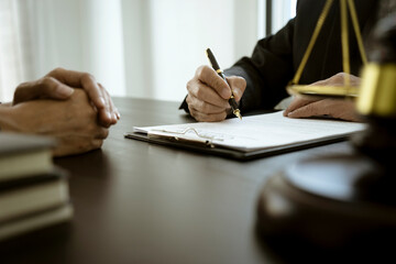 The lawyer is write drafting a legal document while listening to the client's information