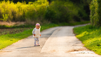 Child on walk outdoors on a rural road leading to forest.