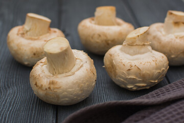 Fresh champignon mushrooms lie on a gray wooden table.