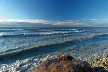 Fototapeta na wymiar Stone on the background of waves, sunny evening.