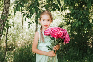 portrait of a happy cute little caucasian seven year old kid girl in light green sundress, holds in...