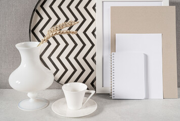 Composition with empty picture frame,notebook,cup of coffee and vase. Elegant working place. Scandinavian interior design.Home office concept.