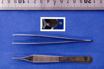 adson toothed forceps on a blue background