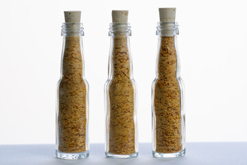 Ground dry Trinidad Scorpion Yellow peppers in three small glass bottles. Flacons are sealed with cork stoppers. 