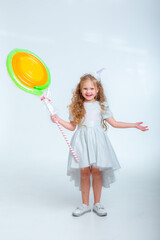 little girl in a birthday hat with a lollipop on a white background studio