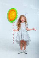 little girl in a birthday hat with a lollipop on a white background studio