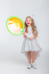 little girl in a birthday hat with a lollipop on a white background studio