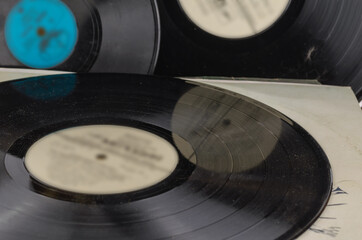 A collection of old vinyl records with defocused lettering in the center.