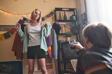 Young woman smoking a cigarette and dancing with young man sitting and drinking wine during retro...