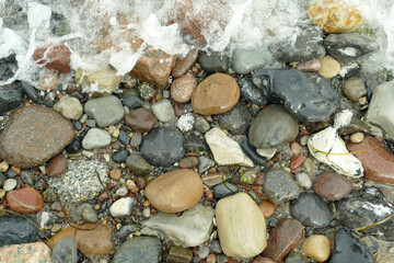 Background: Tiny waves of the incoming sea covering the pebble stones on the beach