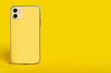 Yellow iPhone 11 in clear silicone case back view isolated on yellow background. Phone case mockup,...