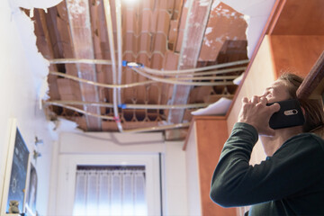 Woman talking to homeowner's insurer while inspecting kitchen ceiling