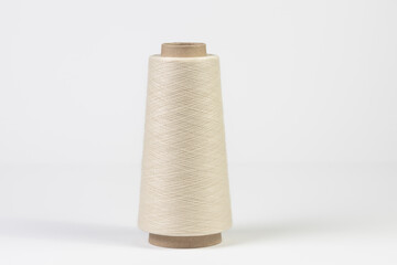Large spool of white woolen thread, close-up with shallow depth of field. Isolated on white...