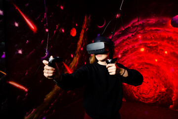 Young beautiful girl in reality reality glasses, glasses for video games, holding gamepads in...