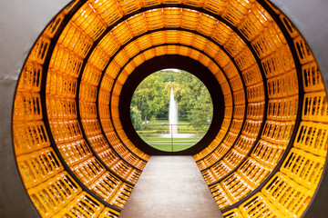 Water fountain among park in circle of construction of orange plastic boxes