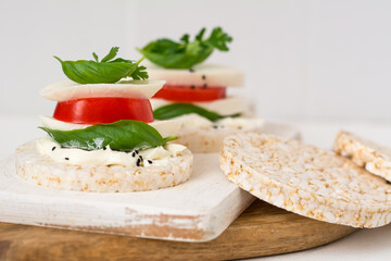 Rice cake sandwich with cheese cream, mozzarella, tomato, basil and spices. A healthy dietary snack