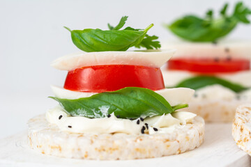 Rice cake sandwich with cheese cream, mozzarella, tomato, basil and spices. A healthy dietary snack
