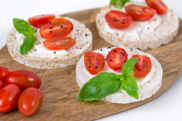 Rice cake sandwich with cheese cream, tomato, basil and spices. A healthy dietary snack