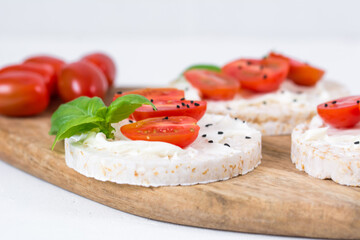 Rice cake sandwich with cheese cream, tomato, basil and spices. A healthy dietary snack