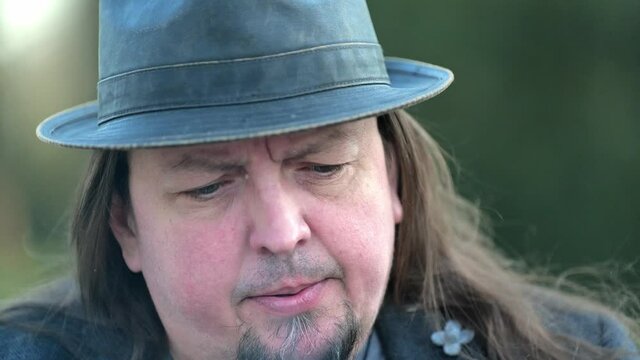 [4k] close up of long haired best ager wearing hat smoking a cigarette