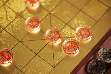 glass pieces of chinese chess on the gold colored chess board