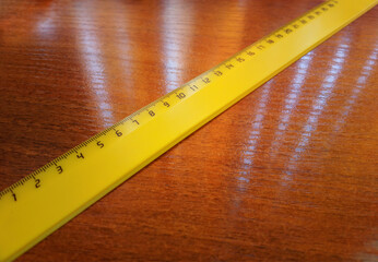 Diagonal yellow ruler on wooden table background