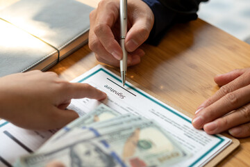 Hands of businessmen agreeing to the offer of bribery by signing a personal benefit agreement The concept of fraud and business practices within the company