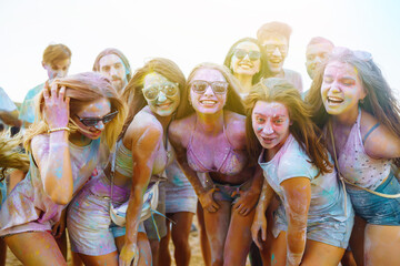 Group of people have fun at the holi festival of colors. Smiling faces in colorful powder....
