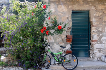 Fototapeta na wymiar Old bike parked in front of a Mediterranean house with beautiful garden. Picturesque scenery on island Lastovo, Croatia. 