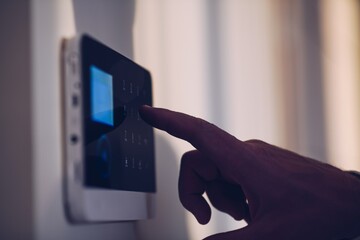 Man's hand unlocking and disarming the home security alarm. Home security concept.