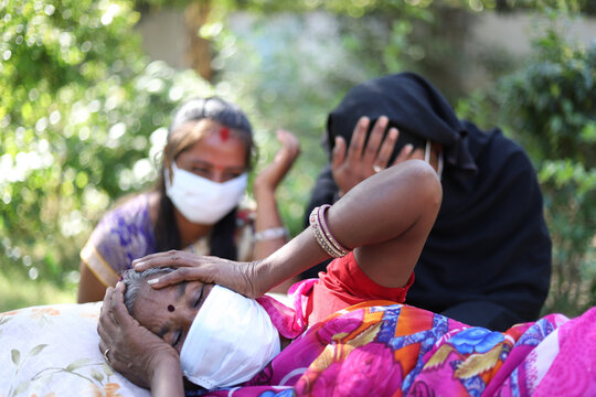 Shallow Focus Shot Of An Old Indian Woman Wearing A Facemask, Lying Down In Pain