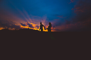 Fototapeta na wymiar pregnant woman and her husband walking in the sunset