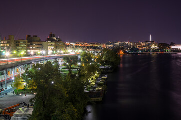 Washington DC skyline with an elevated highway running along the the bank of the Potomac river at night. Light trails.