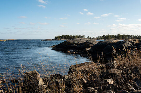 Beautiful afternoon outdoors by the coast in Sweden. Natural rock formation and cliffs, yellow grass and blue sea water with no people around. Photo taken in the archipelago outside Oskarshamn, Sweden